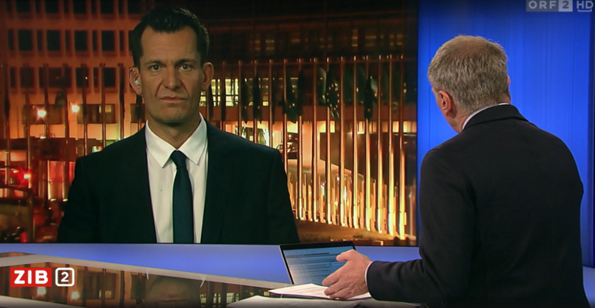 Eine Aufnahme der Sendung Zeit im Bild. Armin Wolf moderiert mit dem Rücken zur Kamera, per Screen zugeschaltet ist Wolfgang Mückstein aus Brüssel