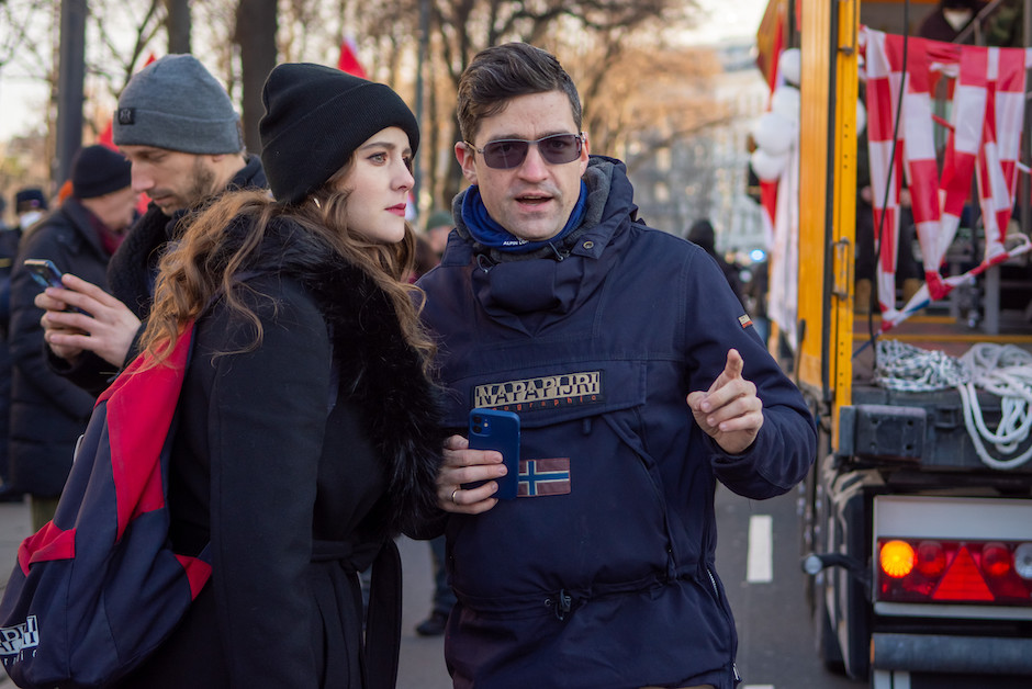 Der Aktivist mit Sonnenbrille am Rande einer Demo, Ehefrau hört ihm zu