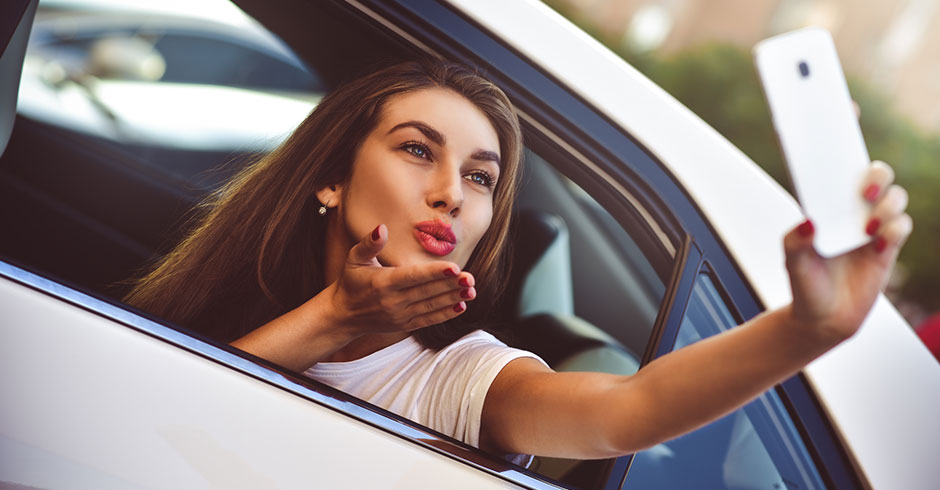 Frau erstellt ein Selfies und wirft einen Kussmund in Richtung Smartphone-Kamera | Credit: iStock.com/NiKita Filippov