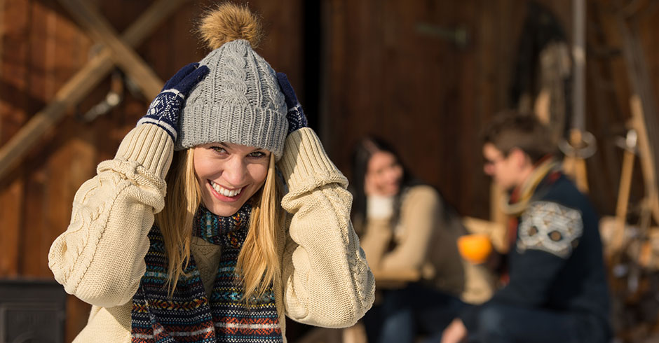 Junge fröhliche Frau vor einer Almhütte bei winterlichen Temperaturen | Credit: iStock.com/CandyBoxImages