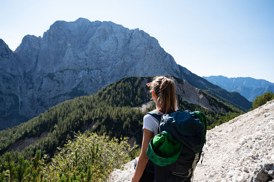 Junge Rucksacktouristin unterwegs in den Bergen | Credit: iStock.com/Gajus