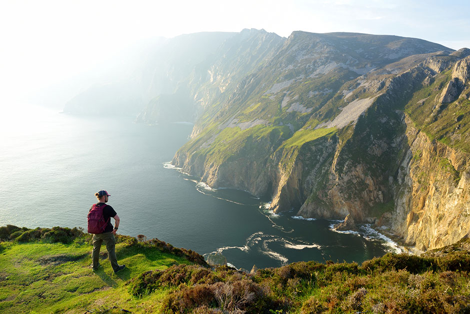 Junger Rucksacktourist an der irischen Steilküste | Credit: iStock.com/MNStudio