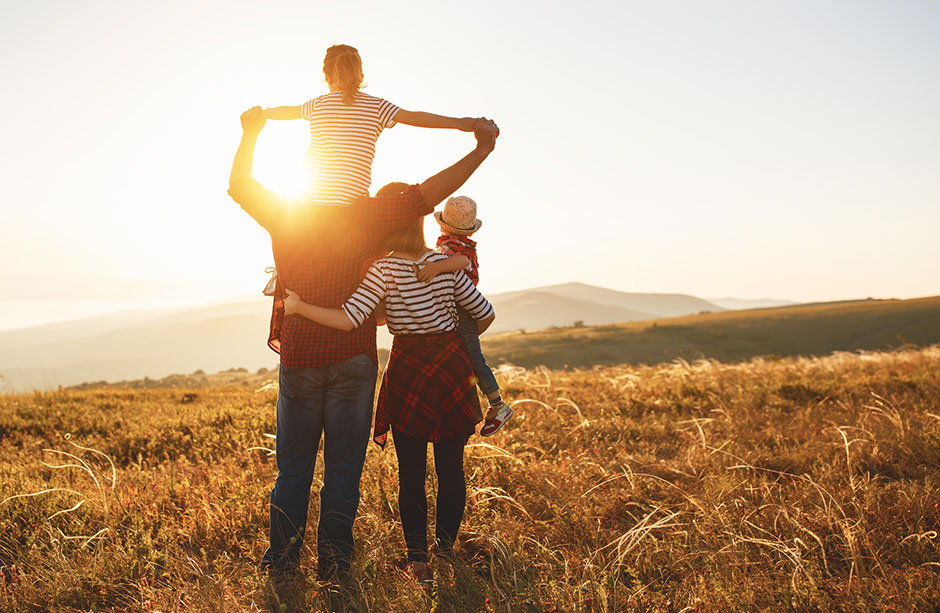 Elternpaar mit seinen beiden Kindern im Sonnenuntergang | Credit: iStock.com/evgenyatamanenko