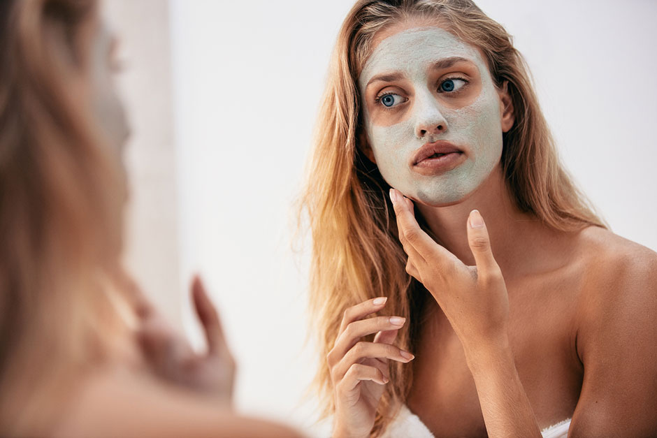 Junge Frau trägt sich eine Gesichtsmaske auf | Credit: iStock.com/Jacob Ammentorp Lund