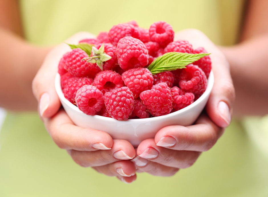 Eine Schüssel Himbeeren in den Händen einer jungen Frau | Credit: iStock.com/alentynVolkov
