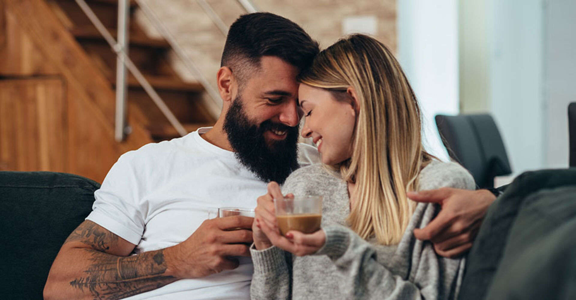 Verliebtes Pärchen Arm in Arm auf der Couch | Credit: iStock.com/zamrznutitonovi