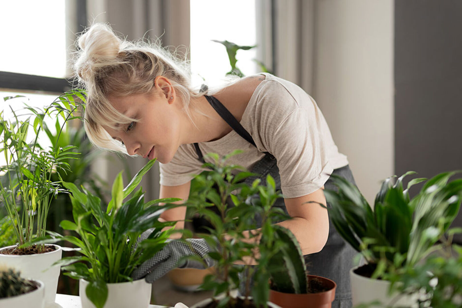 Junge Frau pflegt ihre Pflanzen | Credit: iStock.com/deniskomarov