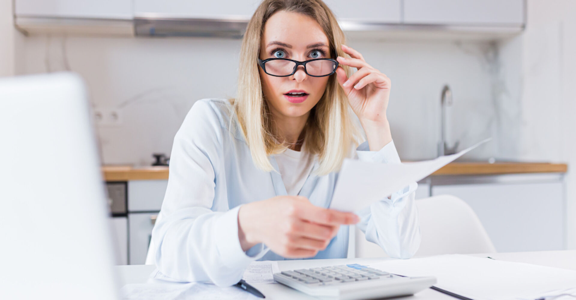 Frau in weißer Bluse mit Brille schaut schockiert | Credit: iStock.com/Liubomyr Vorona