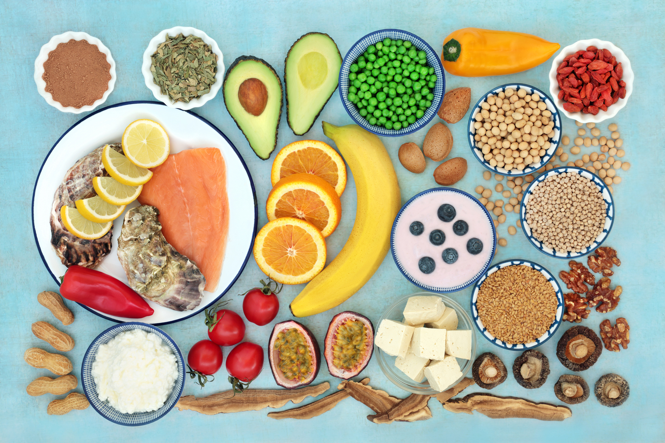 Ein Potpourri gesunder Lebensmittel, von Vollkornprodukten über Obst und Gemüse bis hin zu Fisch, auf einem türkisen Untergrund