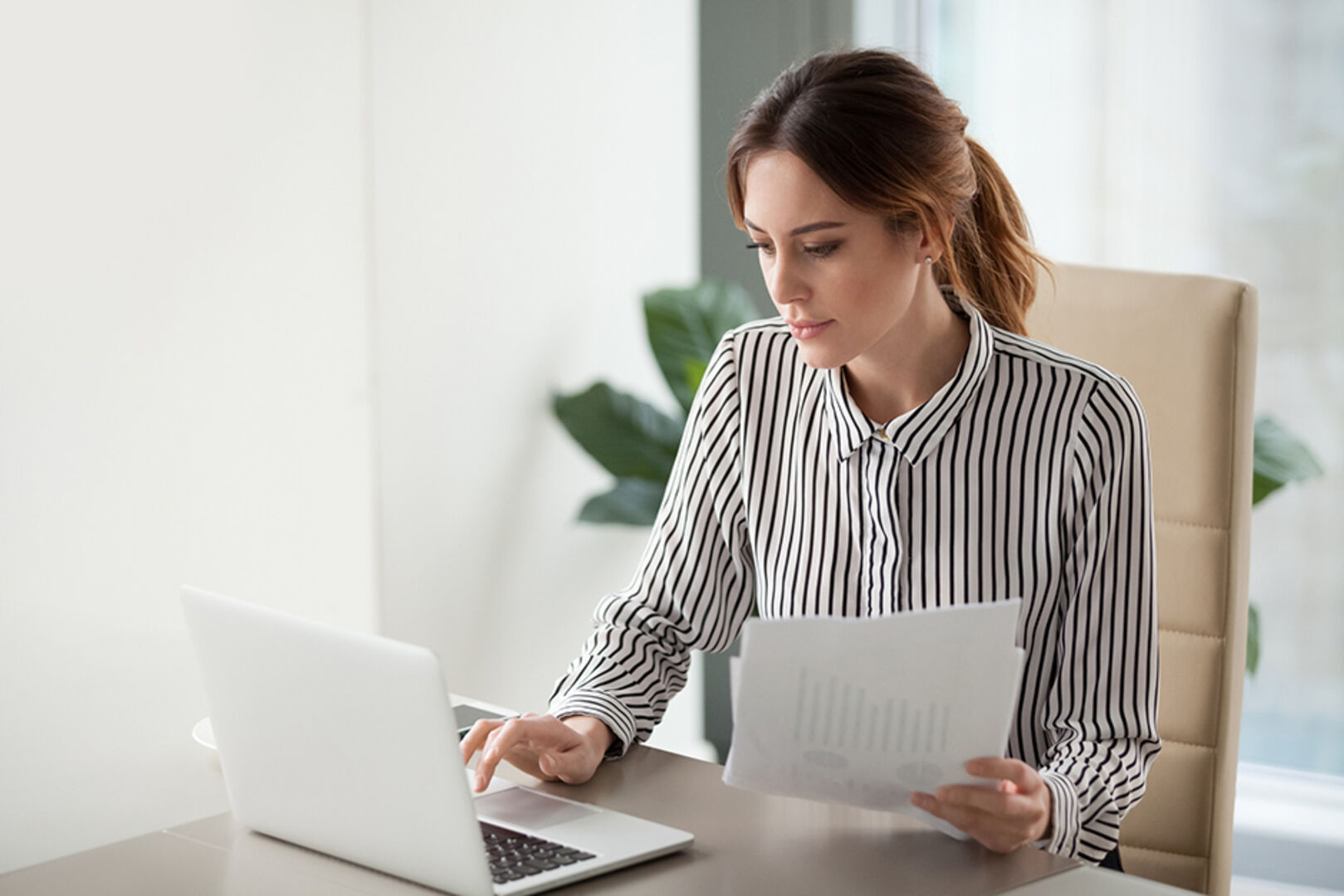 Mitarbeiterin eines Unternehmens während der Arbeit an ihrem Notebook | Credit: iStock.com/fizkes