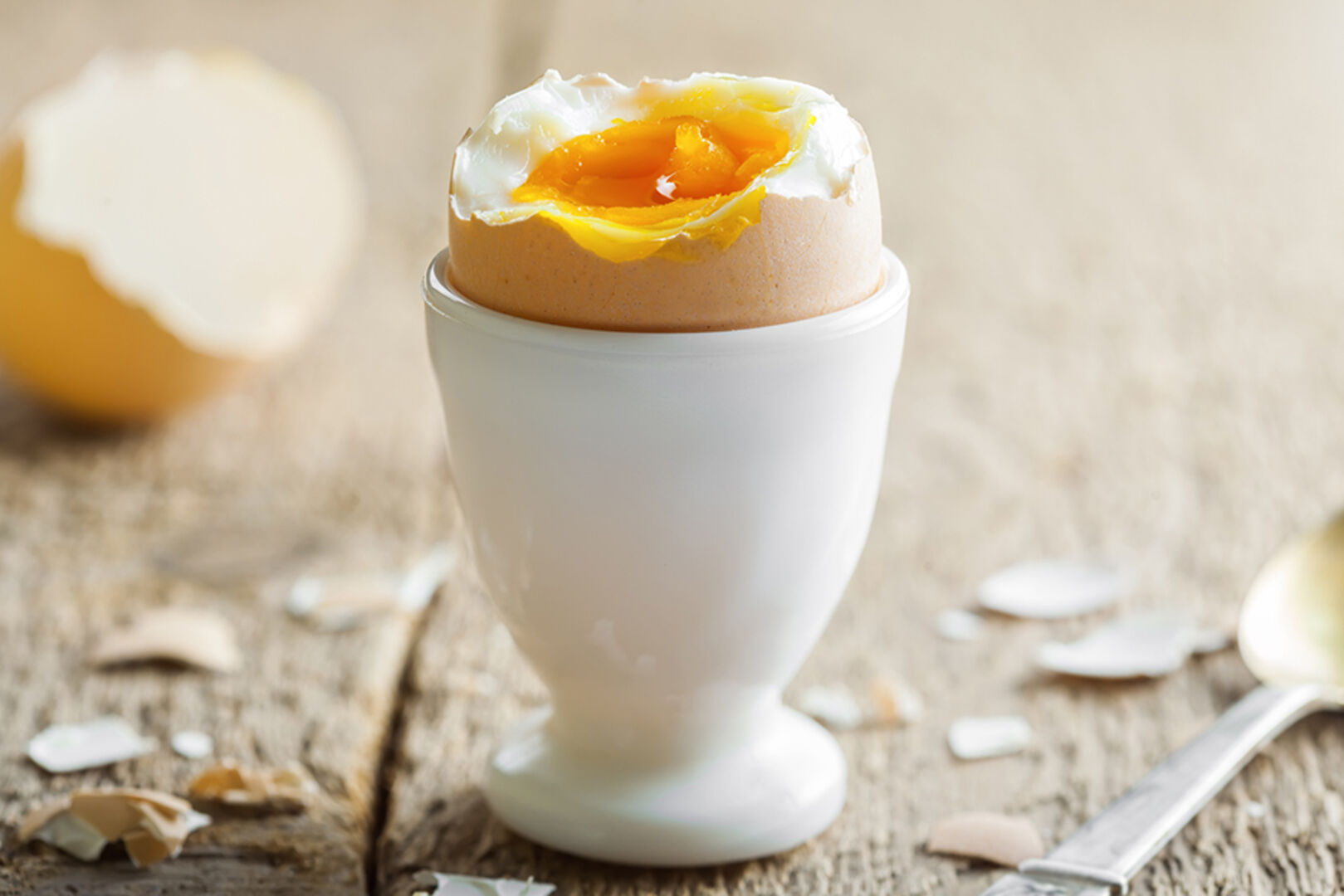 Aufgeschlagenes gekochtes Ei im Eierbecher | Credit: iStock.com/Derkien