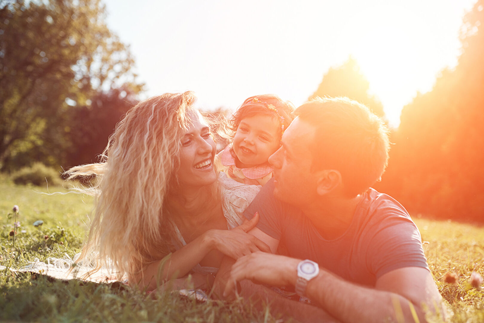 Junges Paar mit kleiner Tochter auf der Wiese an einem strahlenden Sommertag | Credit: iStock.com/ArthurHidden