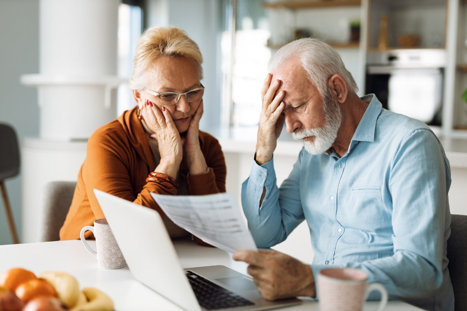 Älteres Ehepaar sitzt über einen Berg Rechnungen | Credit: iStock.com/Goran13