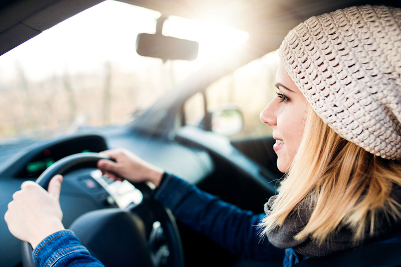 Junge Frau am Steuer ihres Autos | Credit: iStock.com/Halfpoint