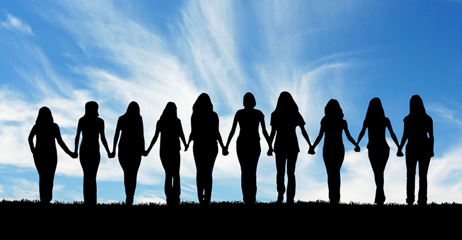Eine Gruppe an Frauen hält sich an den Händen | Credit: iStock.com/HannamariaH