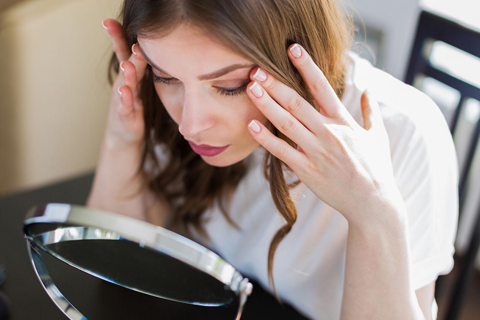 Junge Frau beim kritischen Blick in den Spiegel | Credit: iStock.com/Tinatin1