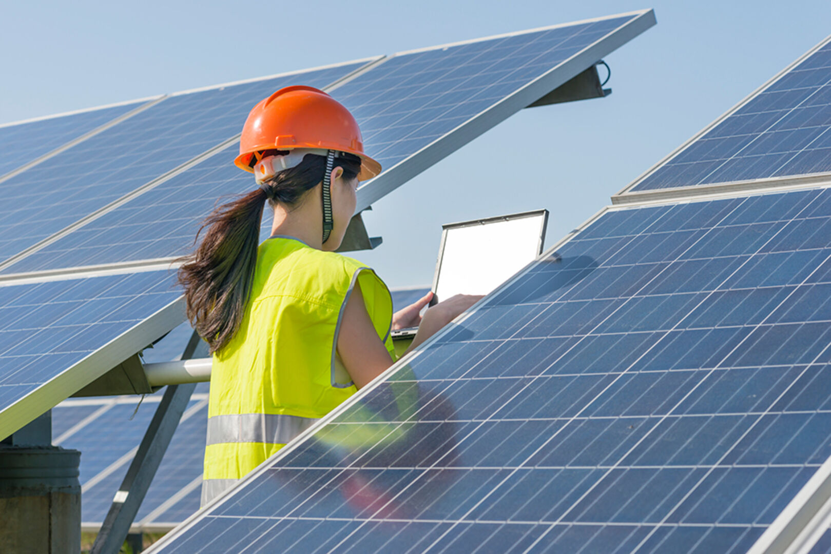 Junge Mitarbeiterin eines Stromnetzanbieters bei der Überprüfung einer Solaranlage | Credit: iStock.com/EllysaHo