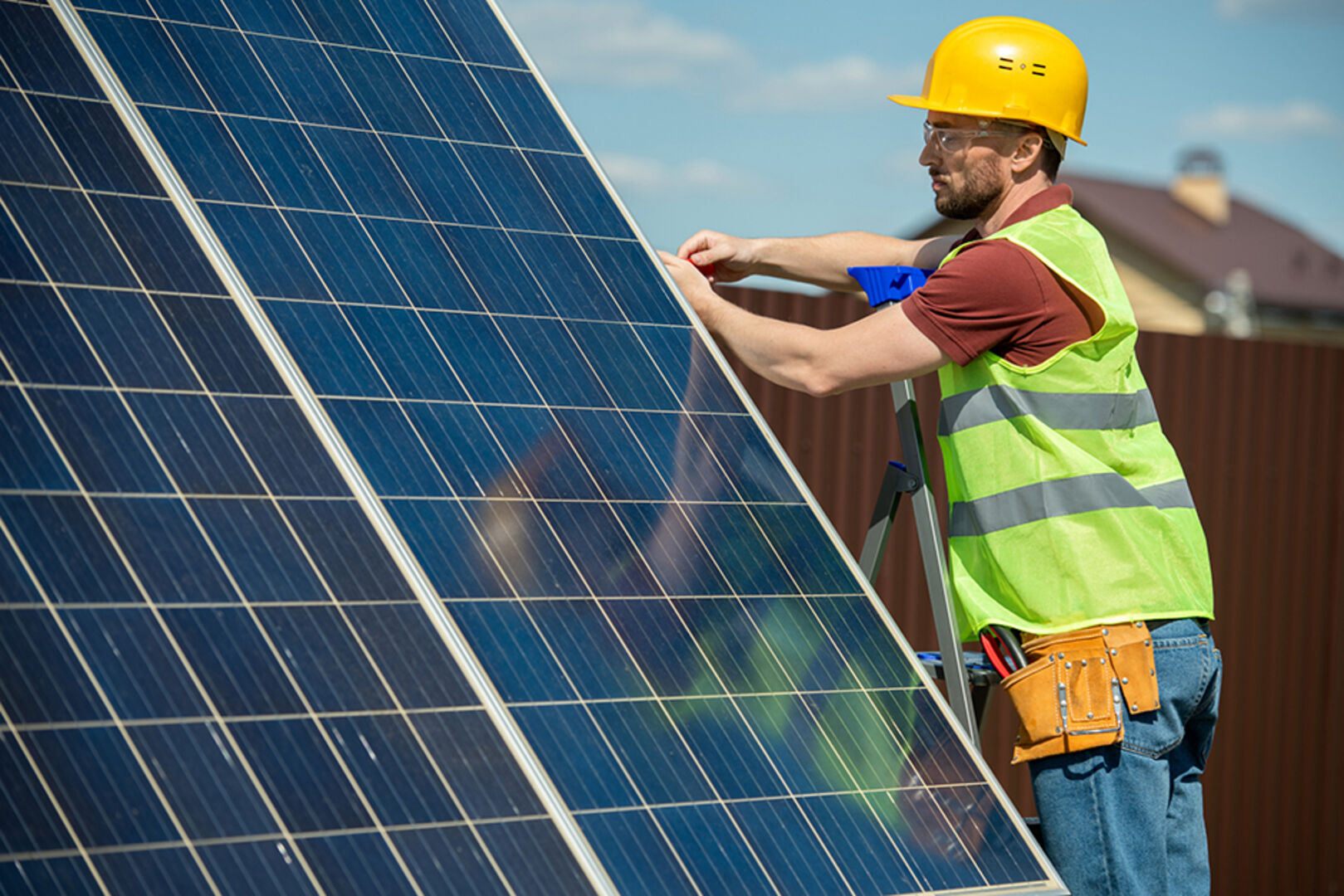 Monteur befestigt Solarmodule auf einem Dach | Credit: iStock.com/shironosov