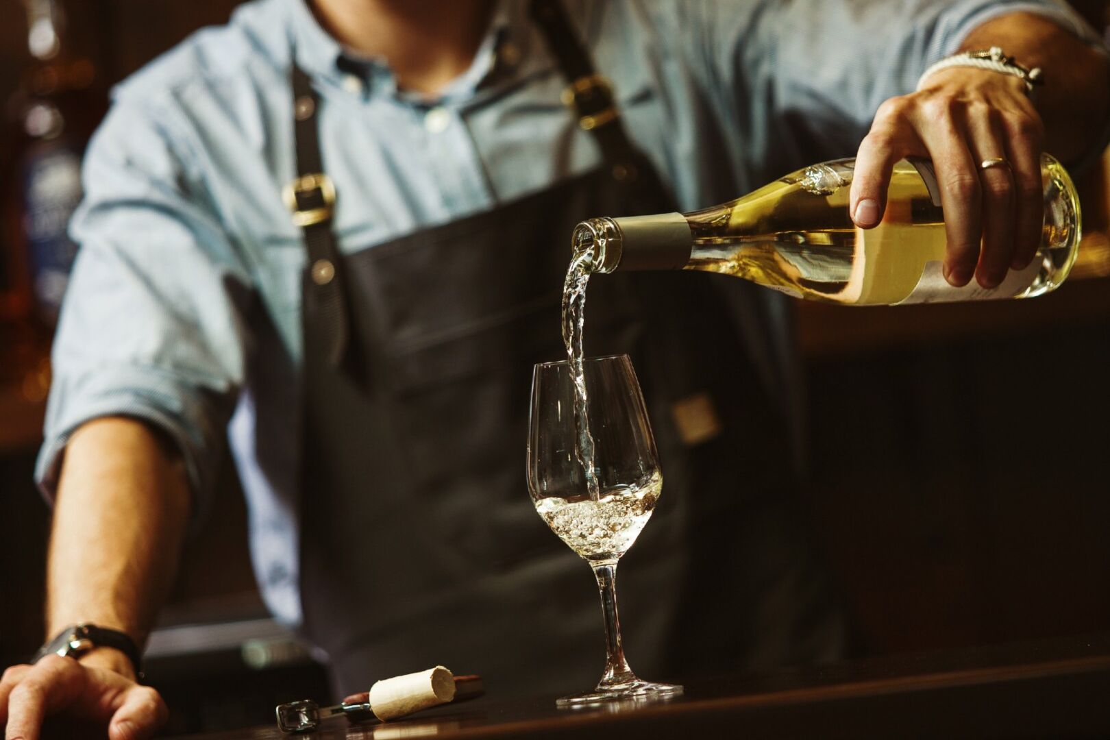 Mann schenkt Weißwein in Glas ein | Credit: iStock.com/IL21
