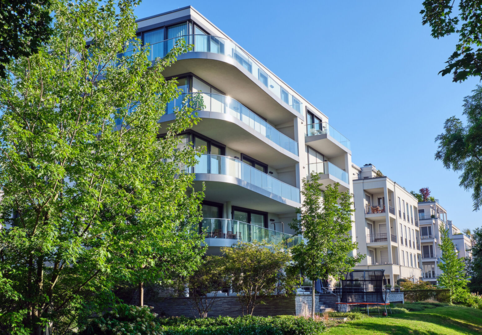 Moderne Wohnanlage mit Begrünung an einem sonnigen Tag | Credit: iStock.com/elxeneize