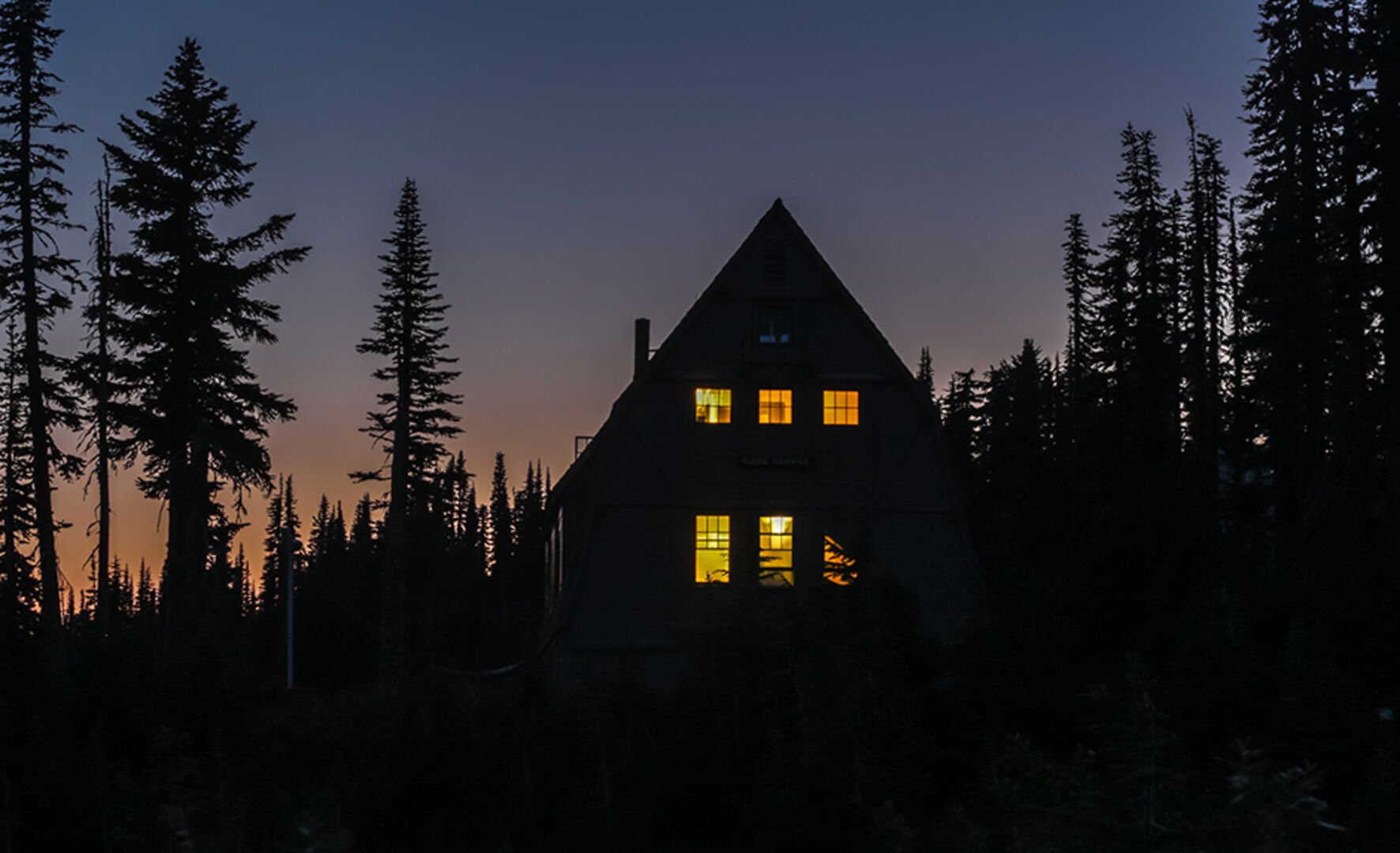 Erleuchtetes Haus bei Dämmerung im Wald | Credit: iStock.com/Lana2011