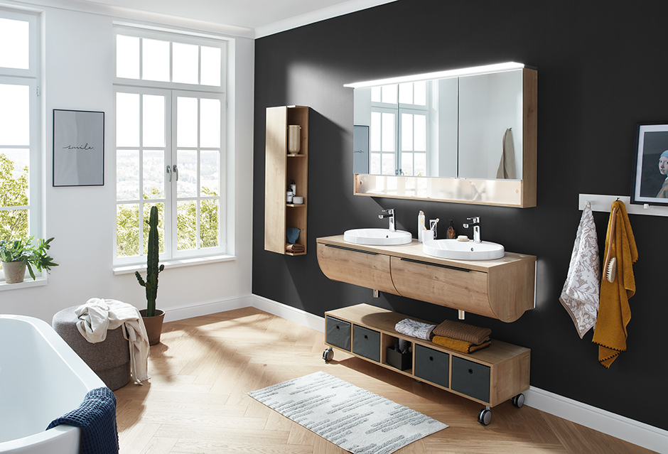 Modernes Badezimmer mit hellen Möbeln vor schwarzer Wand | Credit: XXXLutz