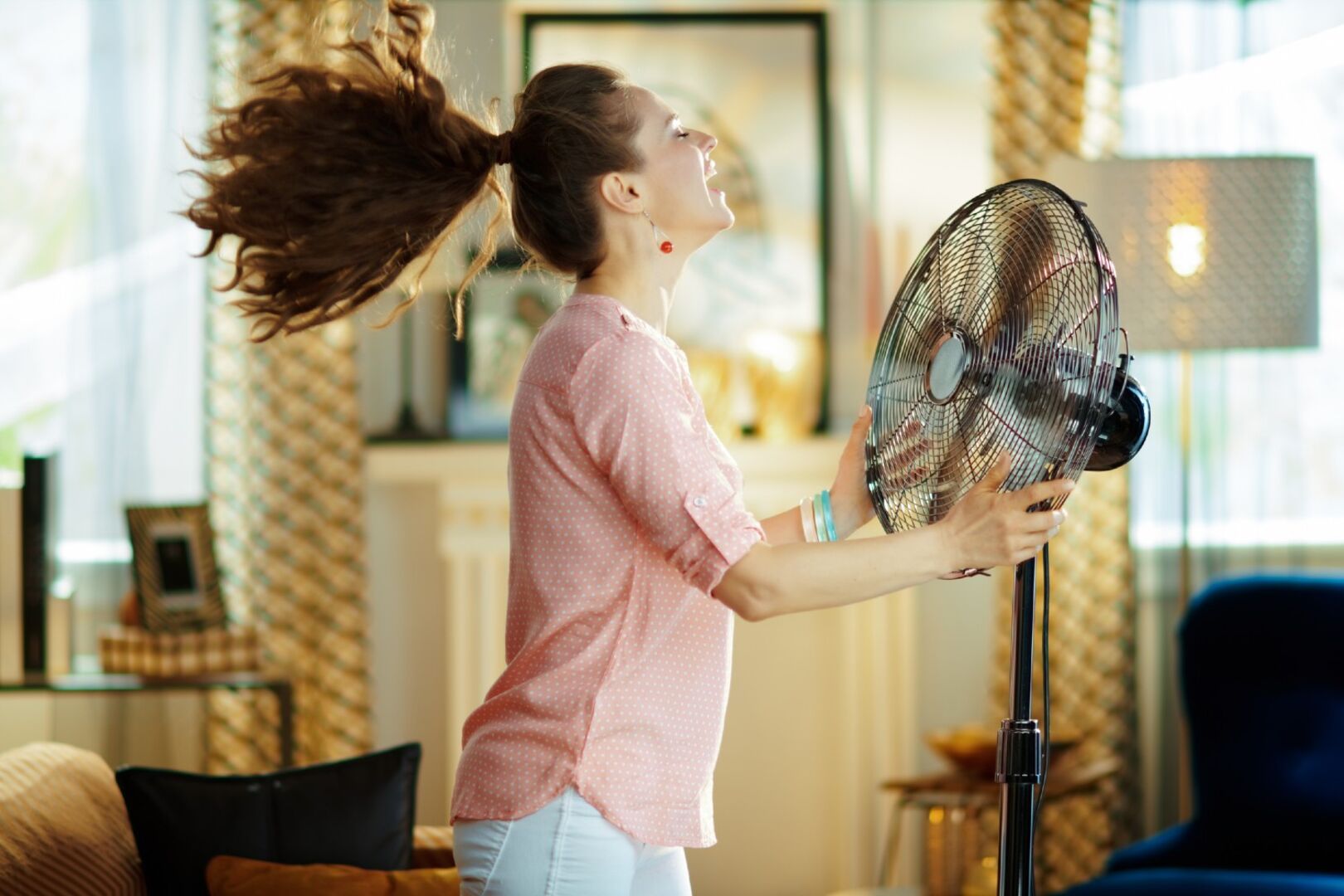 Frau steht vor Ventilator | Credit: iStock.com/CentralITAlliance