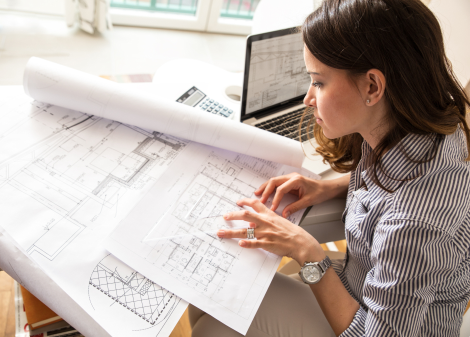 Junge Frau studiert Pläne von Gebäuden | Credit: iStock.com/SolisImages