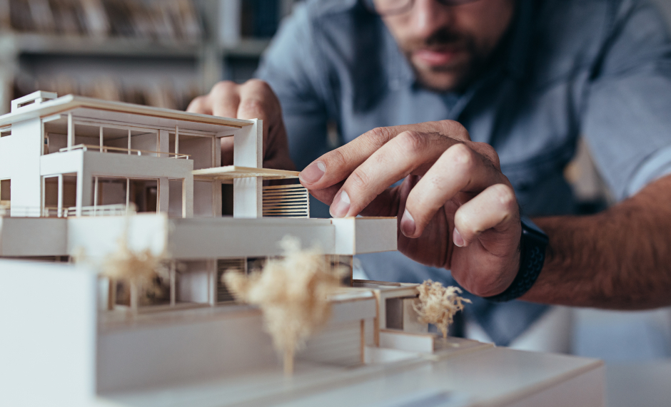 Junger Mann konstruiert ein Energiesparhaus auf dem Reißbrett | Credit: iStock.com/jacoblund
