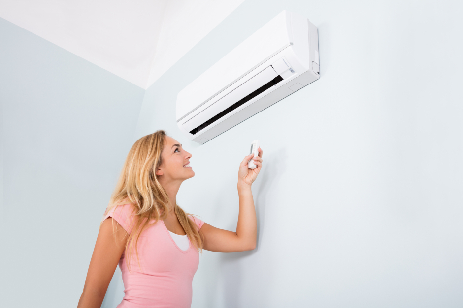 Junge Frau nimmt Klimaanlage in Betrieb | Credit: iStock.com/AndreyPopov