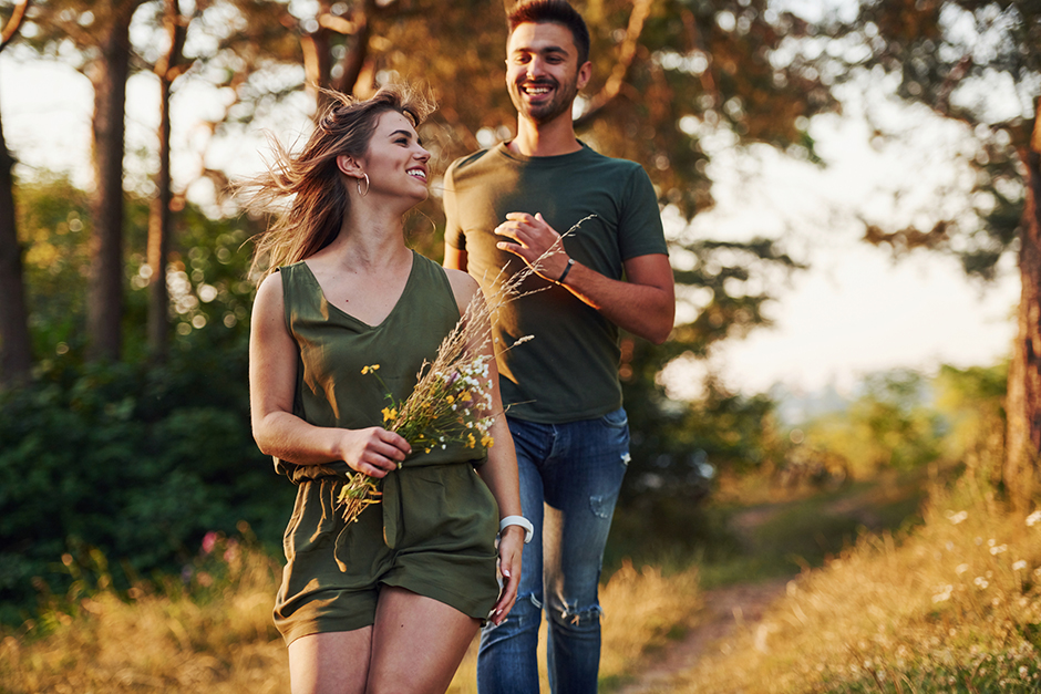 Junges glückliches Pärchen bei einem Waldspaziergang | Credit: iStock.com/standret