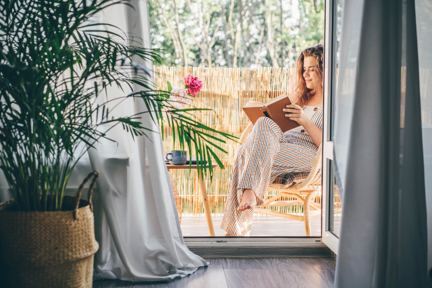 Frau sitzt am Balkon und liest | Credit: iStock.com/Maria Korneeva