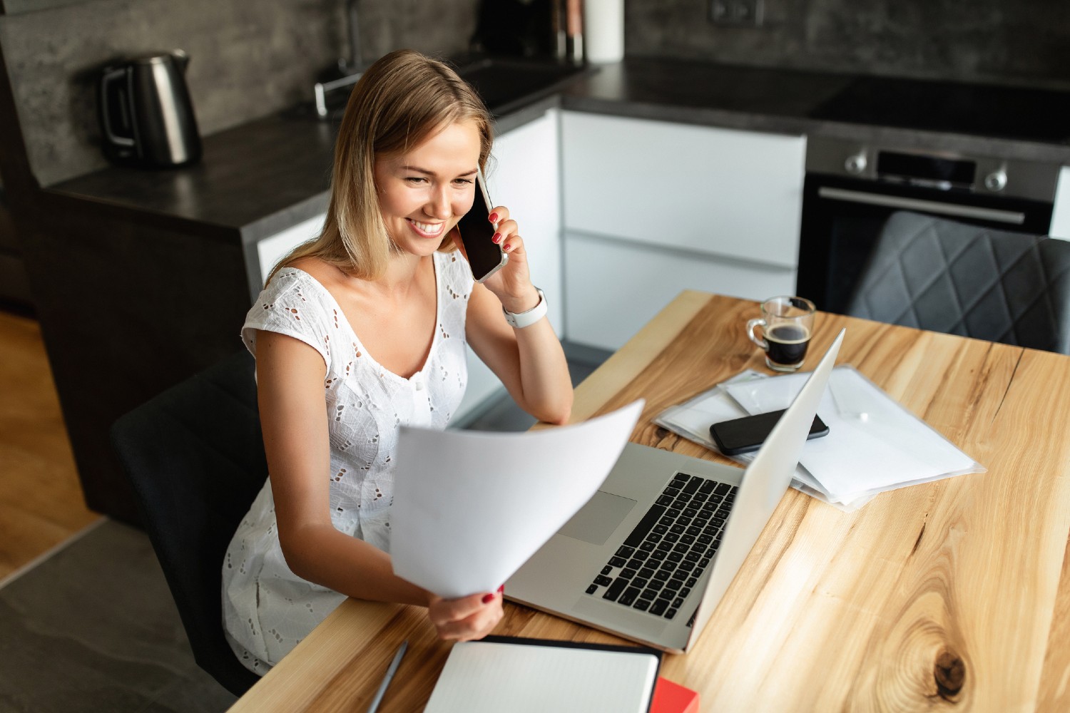 Frau sitzt am Küchentisch und arbeitet | Credit: iStock.com/kkshepel