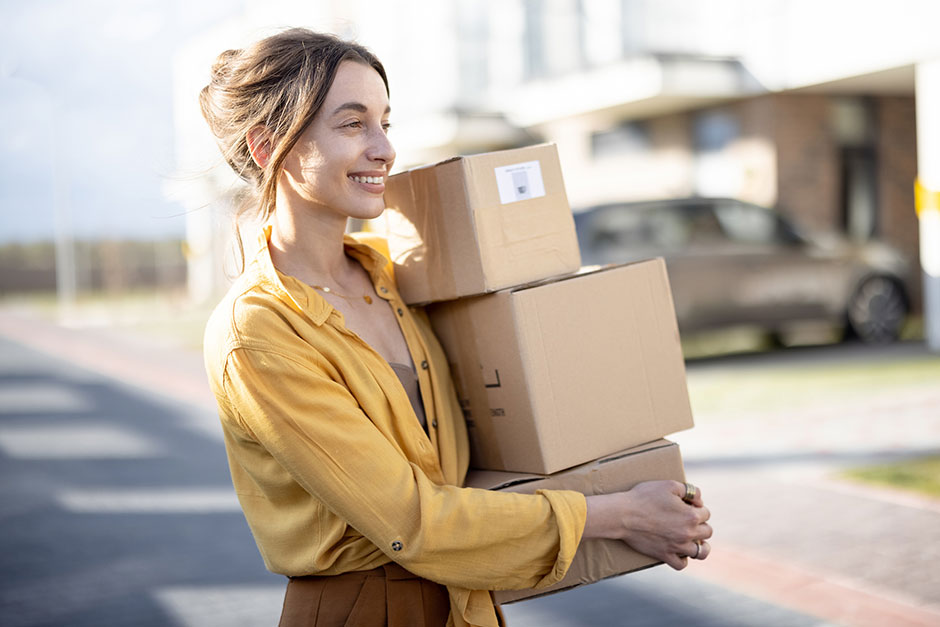 Junge Frau mit Kartons am Arm | Credit: iStock.com/RossHelen