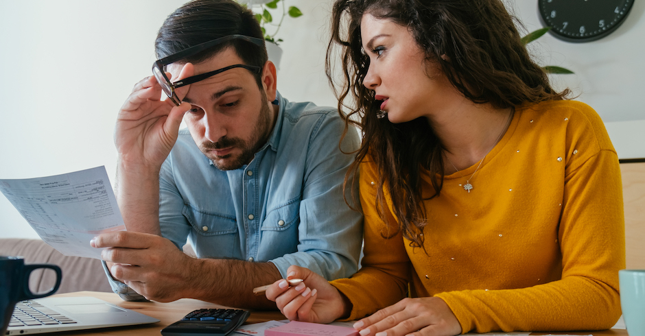 Ein Paar sitzt sorgenvoll über Rechnungen  | Credit: iStock.com/Tijana Simic