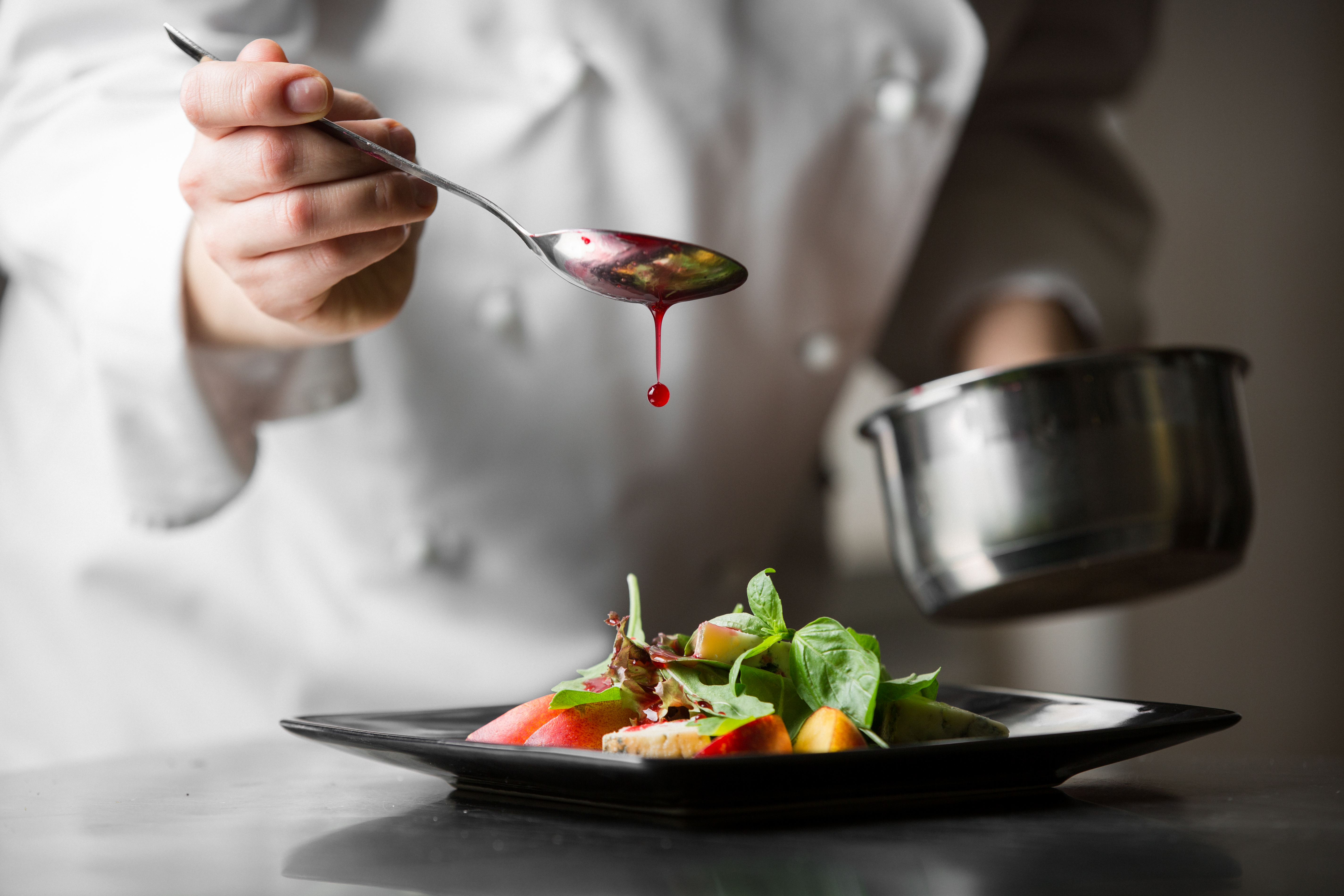 Ein Koch veredelt eine Mahlzeit mit einer Soße