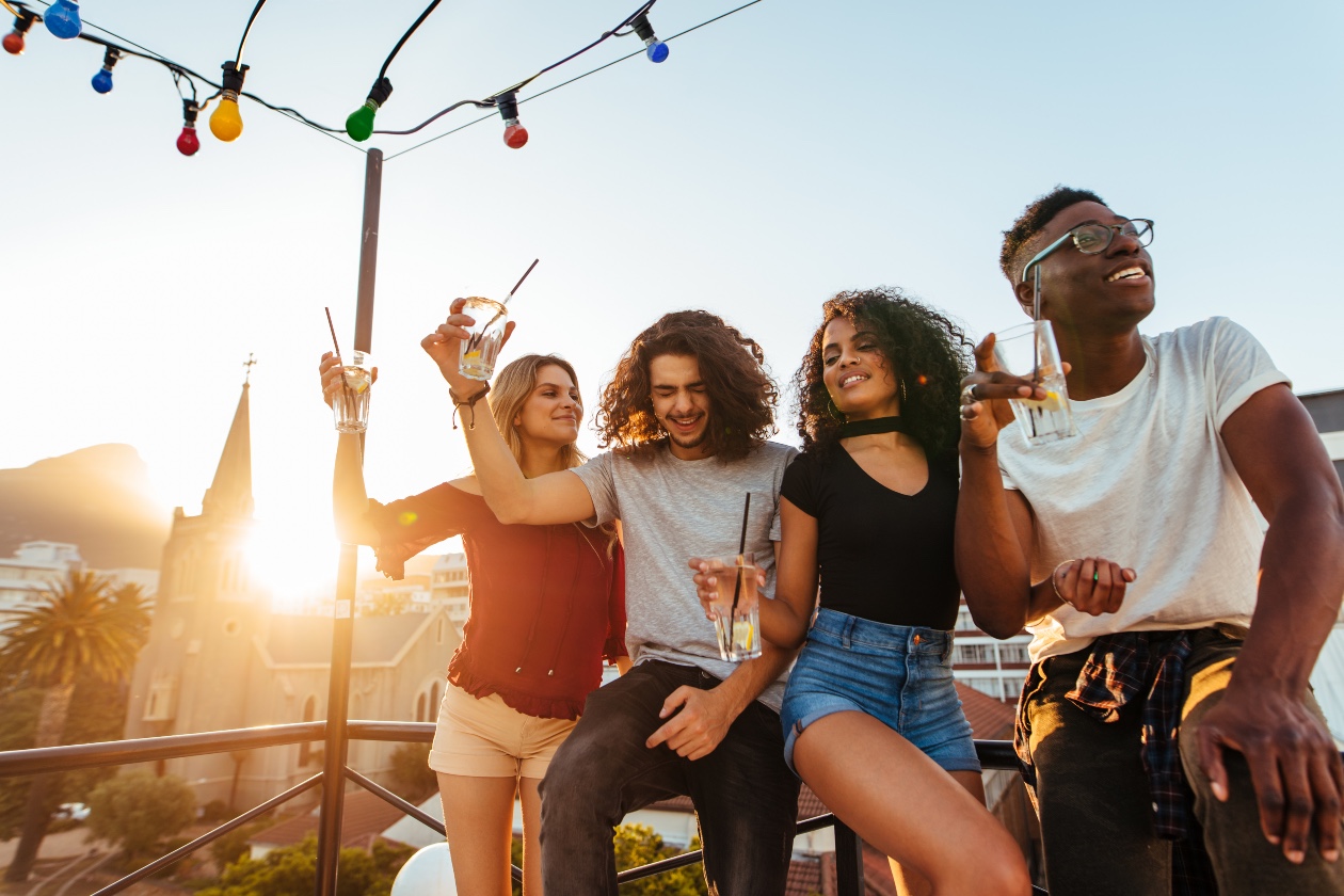 Sonnenuntergang: Vier Junge Menschen feiern auf einer Dachterrasse. | Credit: iStock.com/jacoblund