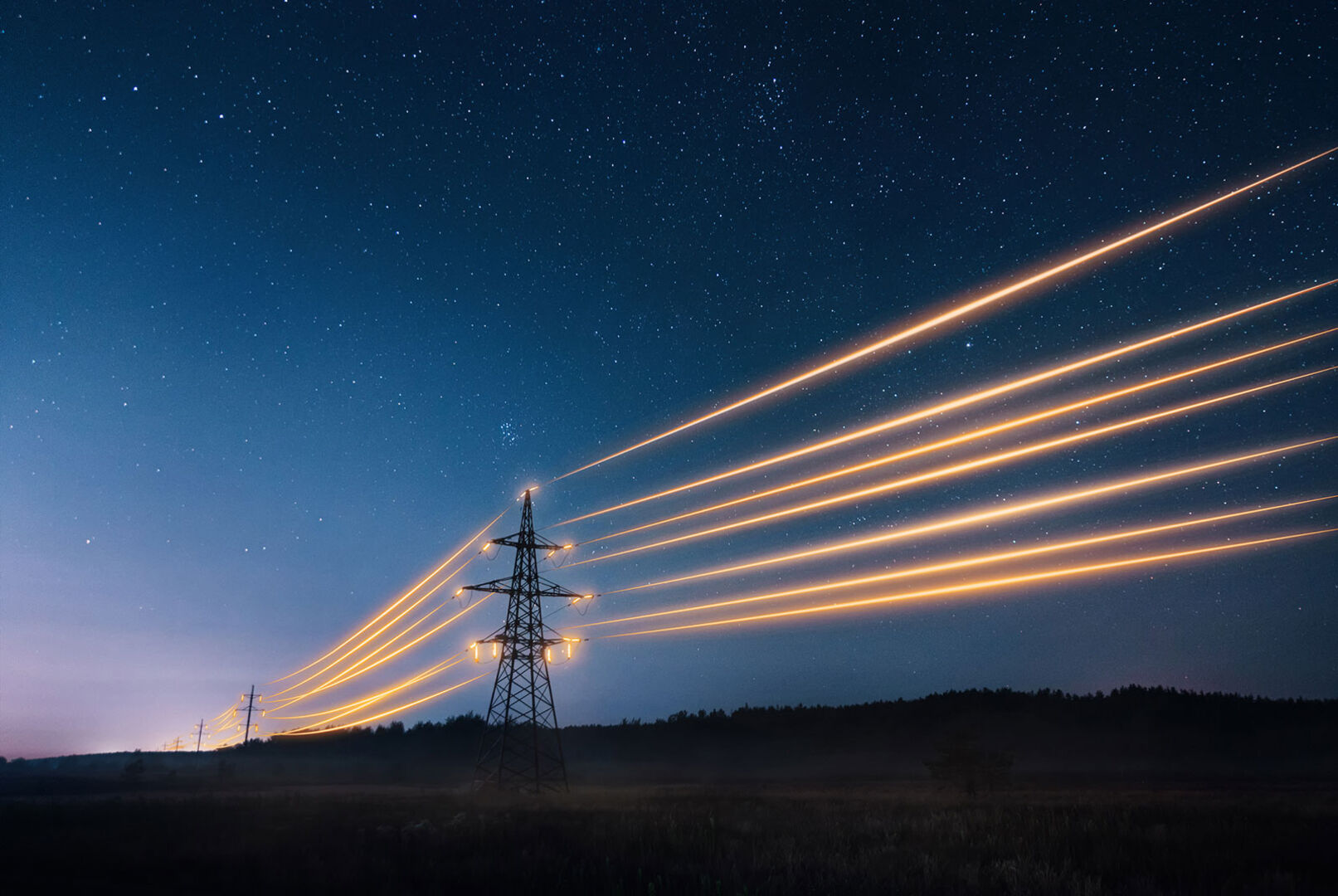 Erleuchtete Stromleitungen in der Nacht | Credit: iStock.com/Artur Nichiporenko