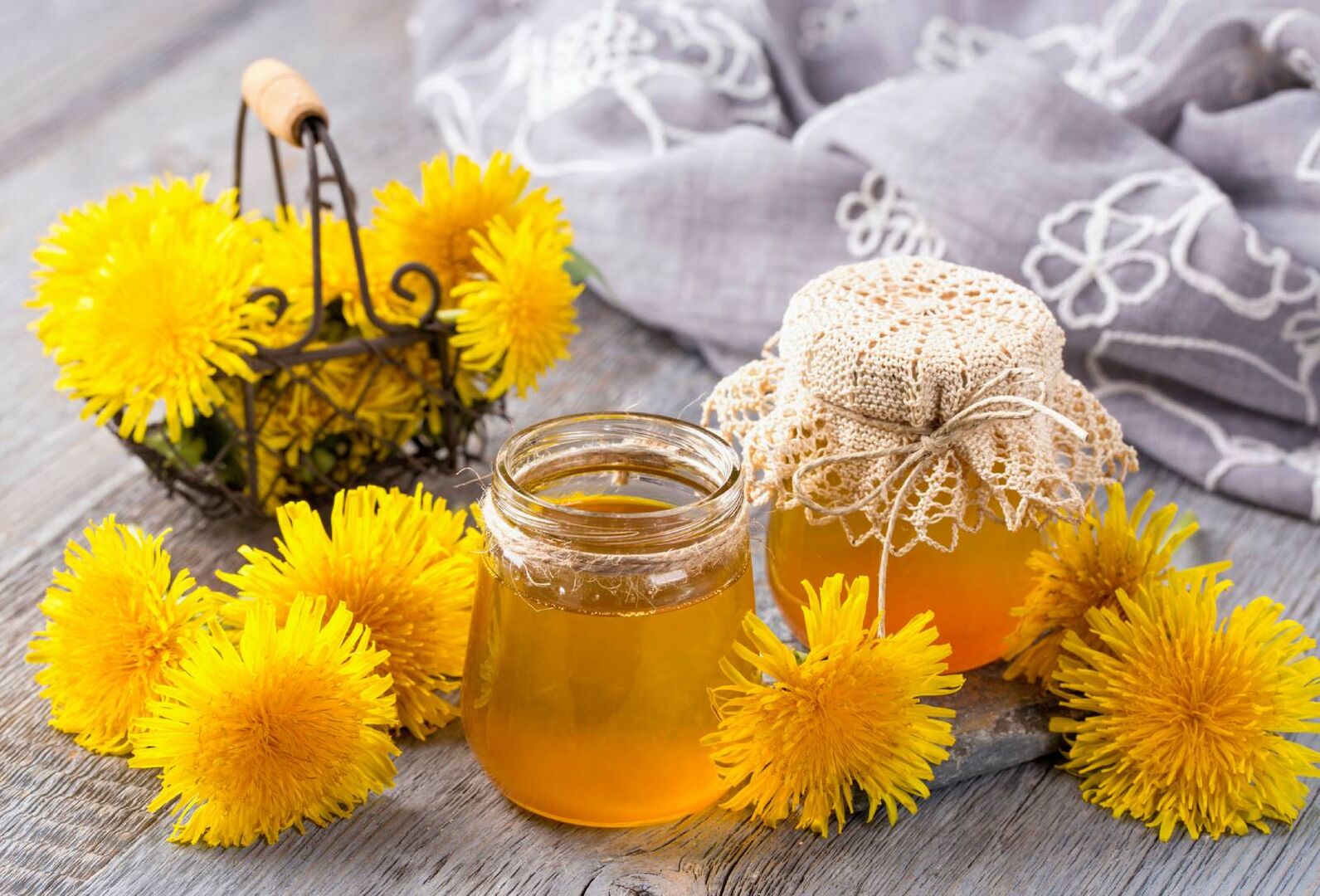 Löwenzahnblüten auf dem Tisch neben einem Glas Honig | Credit: iStock.com/egal