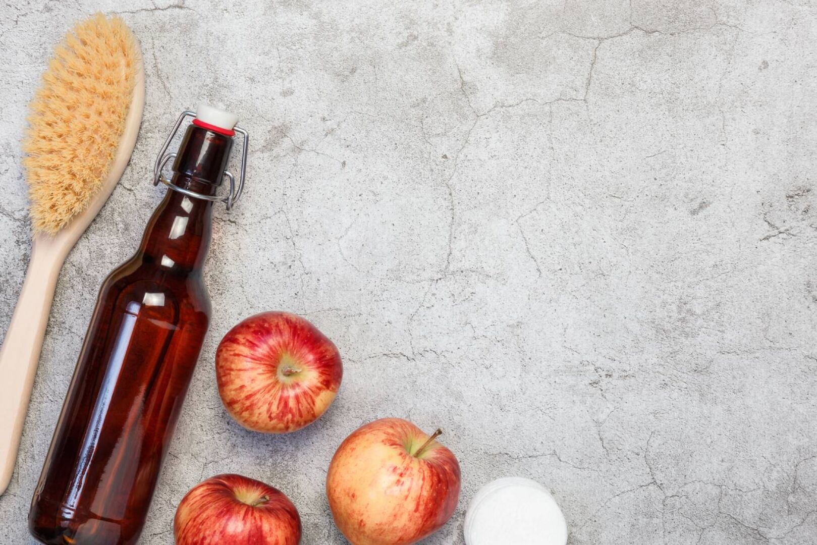 Eine Flasche Essig neben Äpfeln und einer Bürste | Credit: iStock.com/Svetlana Evgrafova