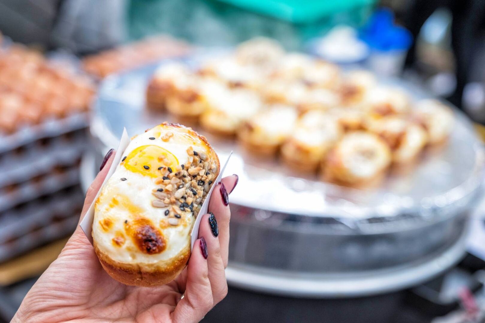 Junge Koreanerin mit einem Snack in der Hand | Credit: iStock.com/SAHACHAT