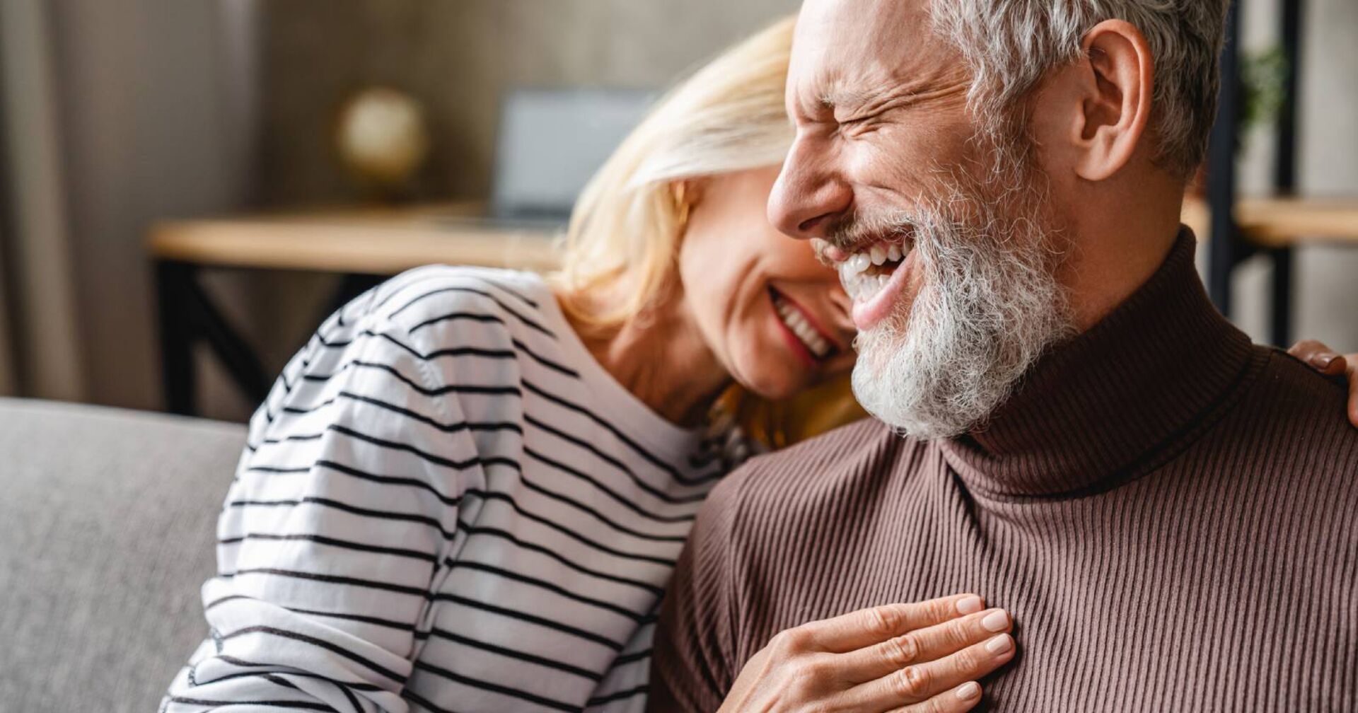 Reiferes Paar lacht gemeinsam auf der Couch | Credit: iStock.com/Inside Creative House