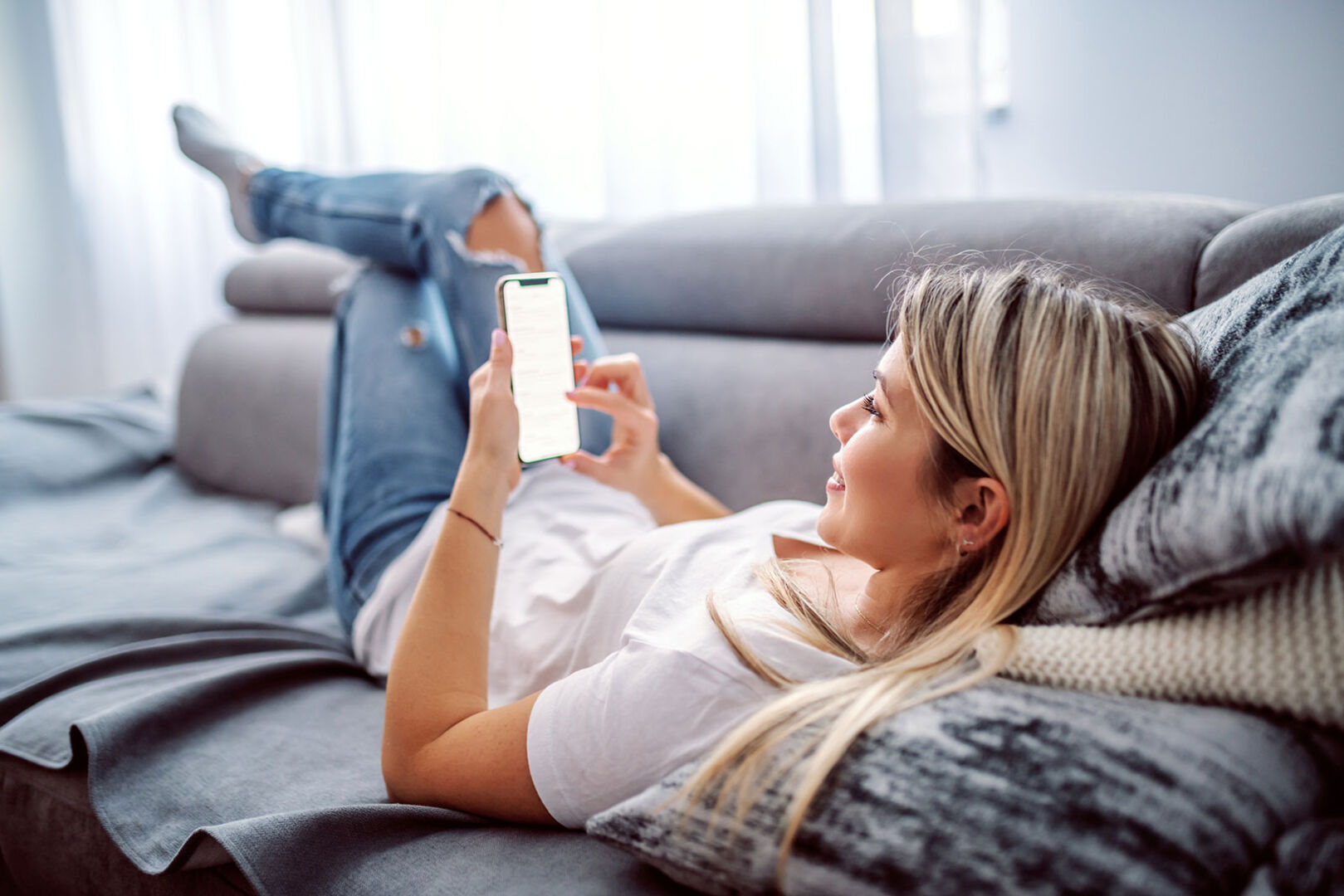 Junge Frau surft via Smartphone im Netz | Credit: iStock.com/dusanpetkovic