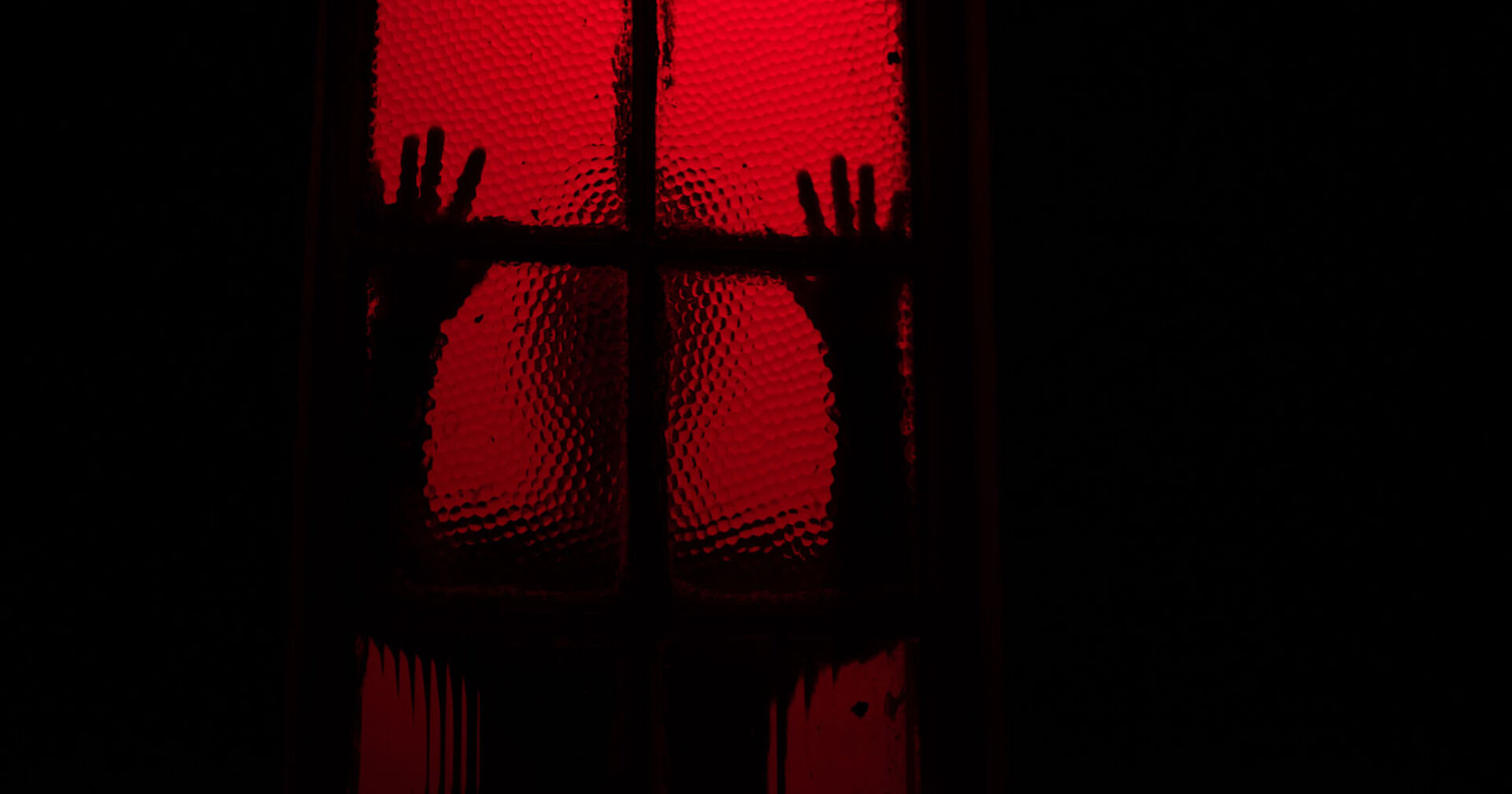 Schatten eines Menschen hinter einem rot erleuchteten Fenster | Credit: iStock.com/rushay booysen