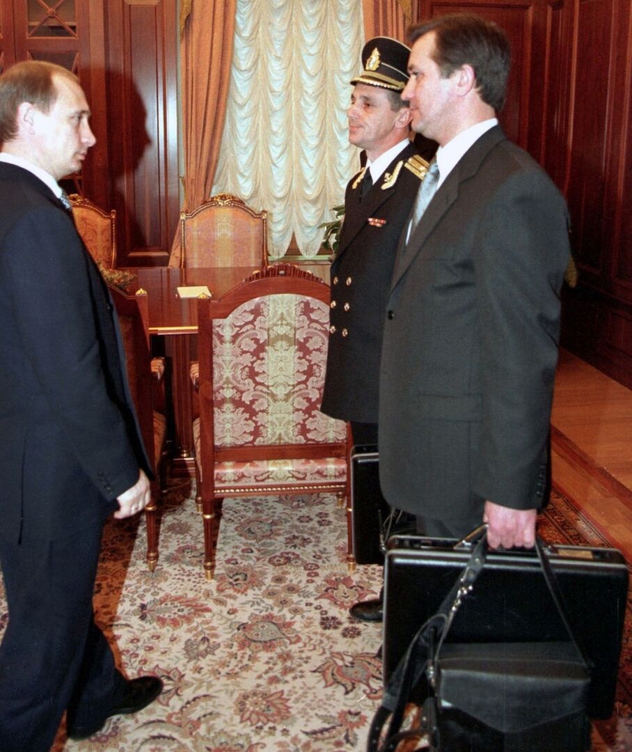 Putin steht zwei Männern gegenüber, einer in Uniform