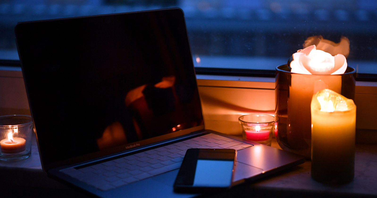Ausgeschaltete Geräte und Kerzen auf Tisch bei Dämmerung