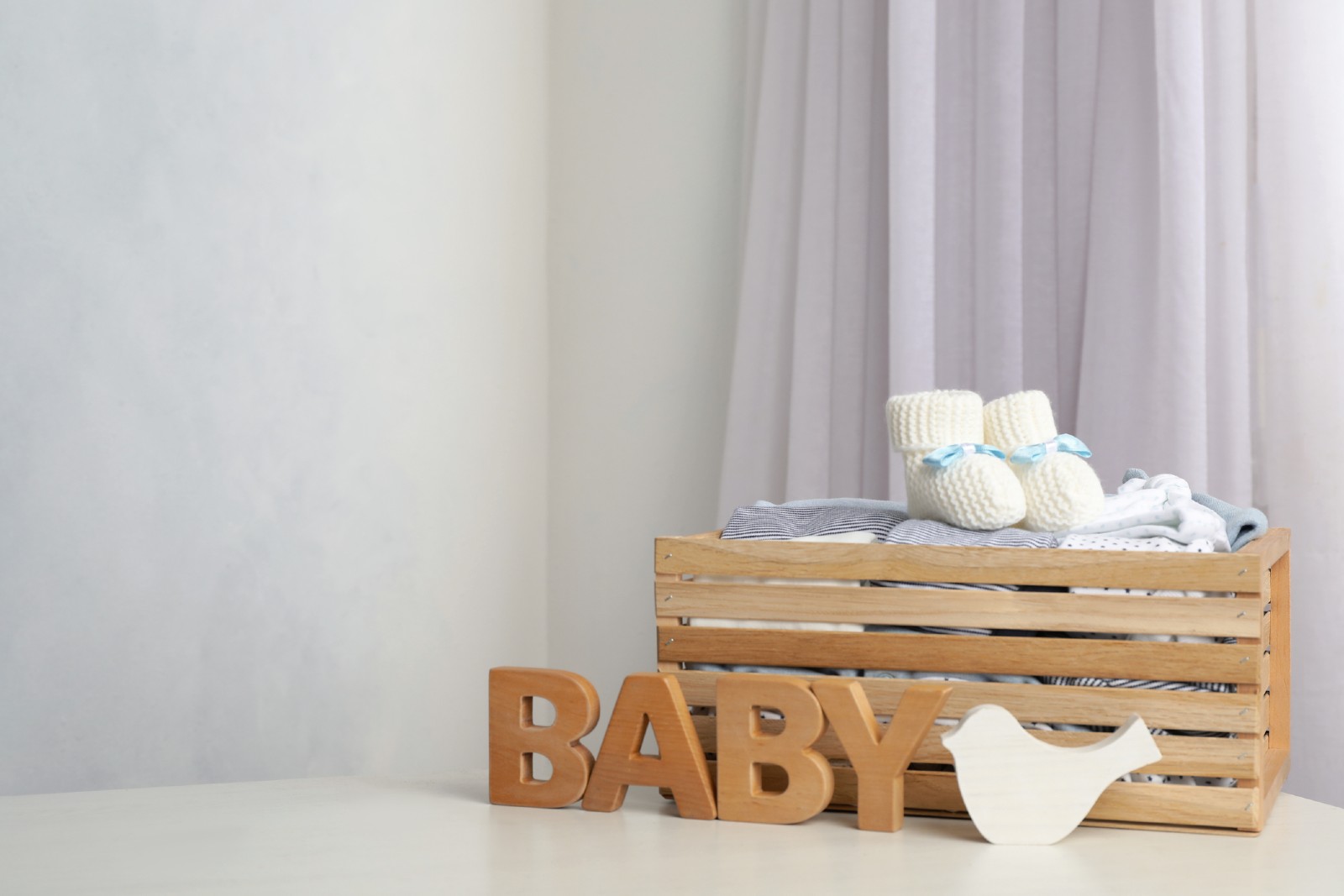 Das Wort "Baby" in Holzbuchstaben steht vor einer Holzkiste | Credit: iStock.com/Liudmila Chernetska