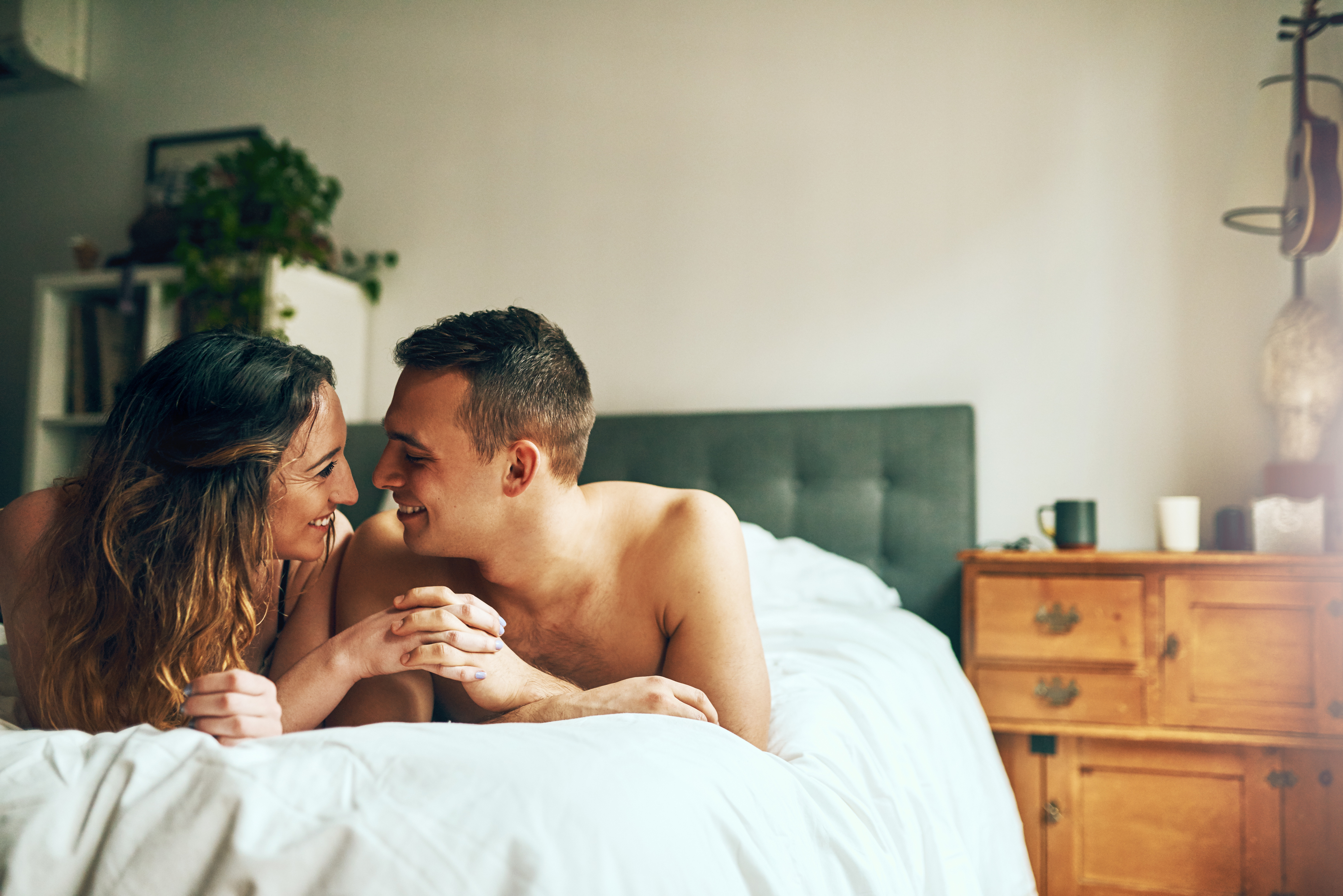 Frau und Mann liegen im Bett und blicken sich in die Augen