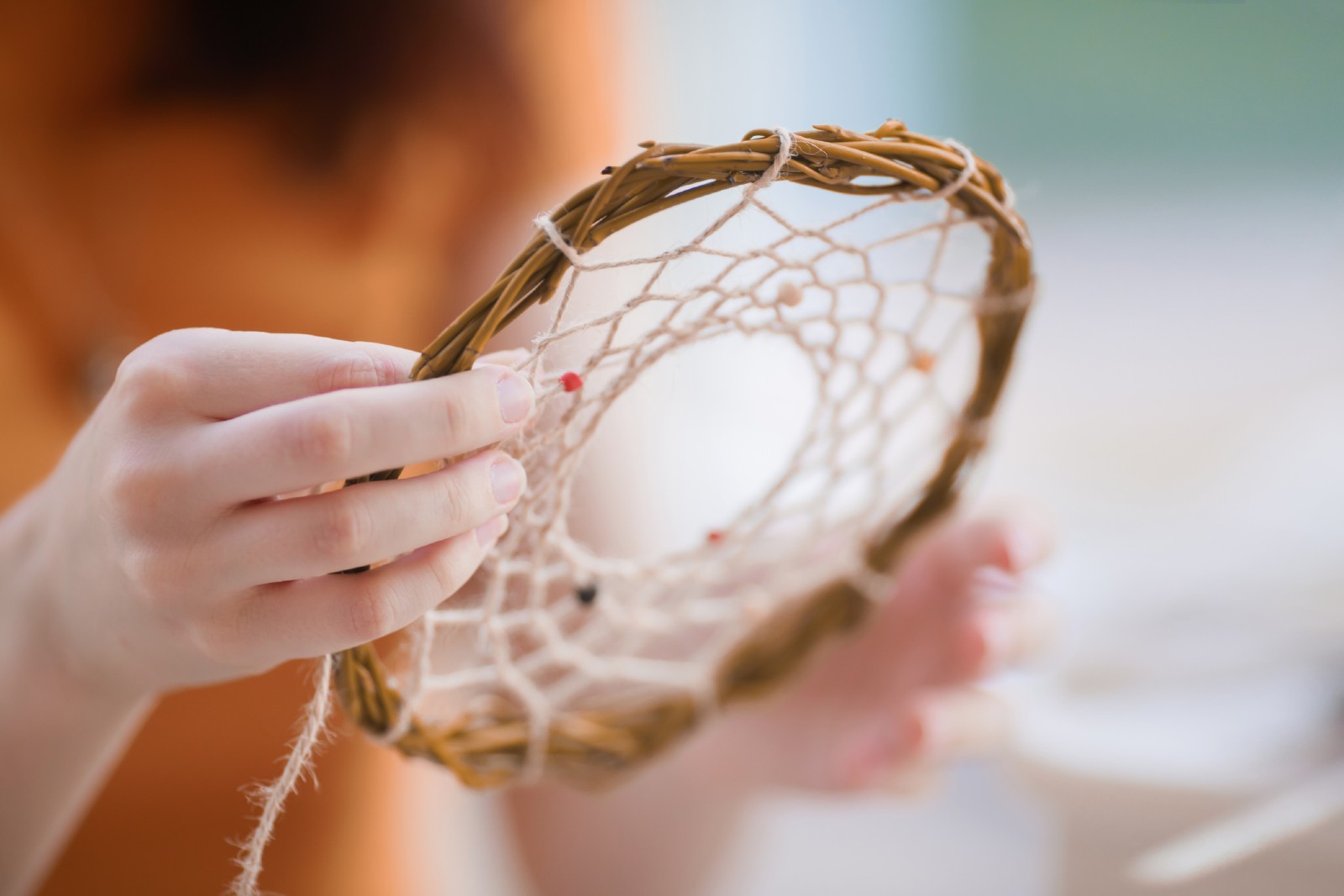 Frau bastelt einen Traumfänger aus Ästen | Credit: iStock.com/Alina Demidenko