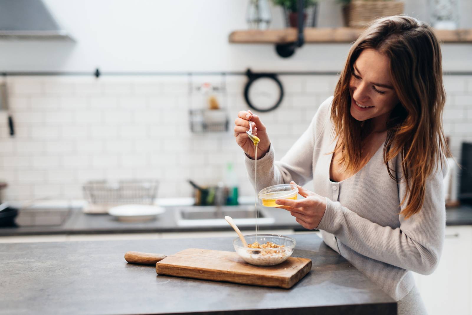 Junge Frau mixt sich Honig in das Müsli | Credit: iStock.com/undrey